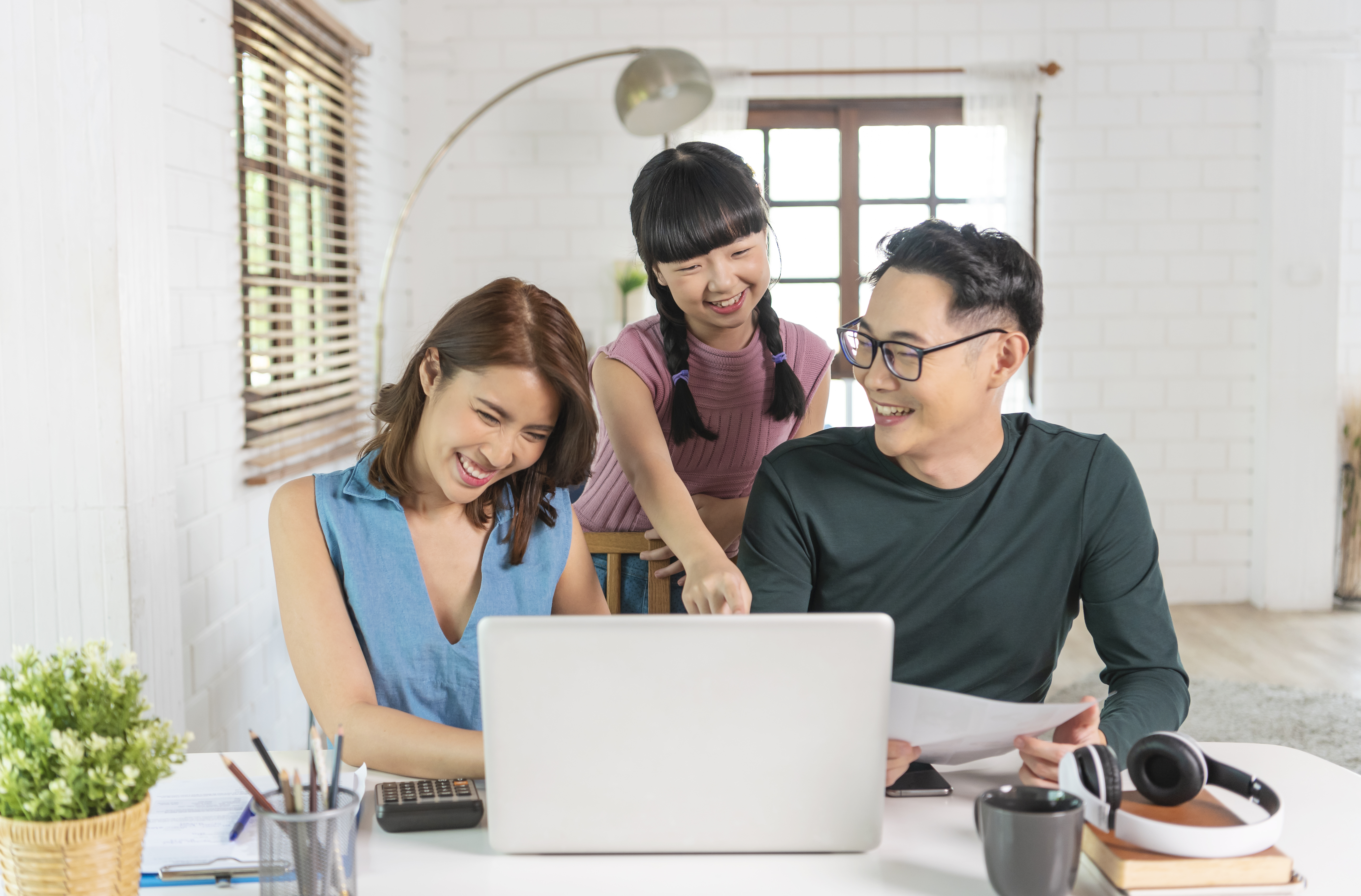 Happy Asian family using computer laptop together on desktop at